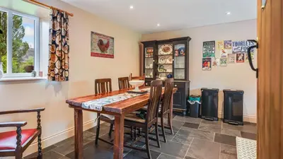 a dining room with a wooden table and chairs at Mwsogl - Luxurious Family Fishing Lodge Near Aberaeron With Private Fishing in Cross Inn
