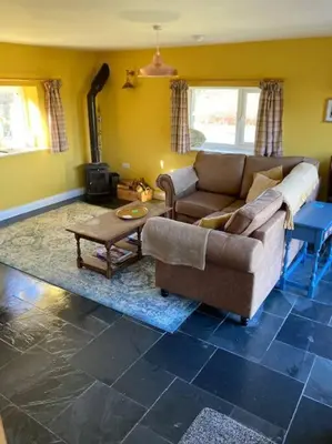 a living room with a couch and a table at Rhedyn - Cosy Fishing Lodge Near Aberaeron in Cross Inn
