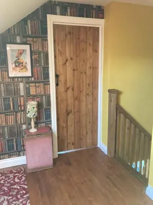 a room with a door and a wall of books at Rhedyn - Cosy Fishing Lodge Near Aberaeron in Cross Inn