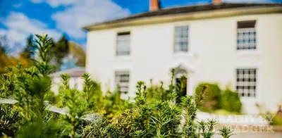 a white house with trees in front of it at Penygelli Apartments in Newtown