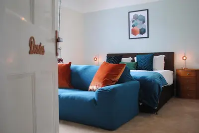 a living room with a blue couch and a bed at Penygelli Apartments in Newtown