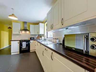 a large kitchen with white cabinets and black appliances at 5 Bed in Llanybydder oc-75907 in Llanwenog