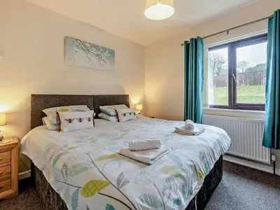 a bedroom with a bed with blue curtains and a window at 5 Bed in Llanybydder oc-75907 in Llanwenog