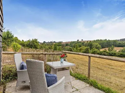 a table with chairs and a vase of flowers on a patio at 2 Bed in Leominster oc-78637 in Stoke Prior