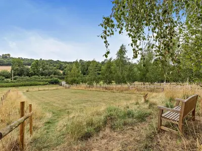 a wooden bench sitting in a field with a fence at 2 Bed in Leominster oc-78637 in Stoke Prior