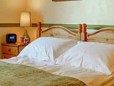 a bed with a wooden headboard and a table with a lamp at 2 Bed in Lampeter oc-43293 in Tregaron
