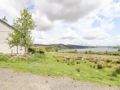 a house with a tree next to a body of water at Craig Yr Ronwy in Bala
