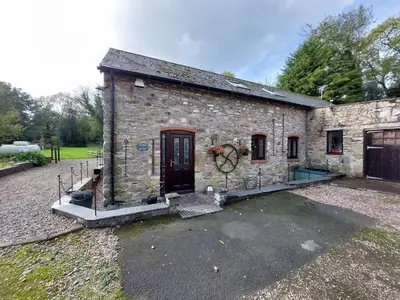 a stone building with a black door and a yard at The Barn at the Mill in Selattyn