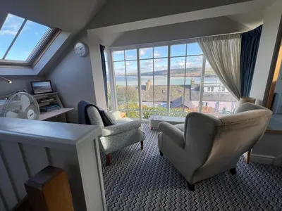 a living room with chairs and a large window at Y Stabl in New Quay