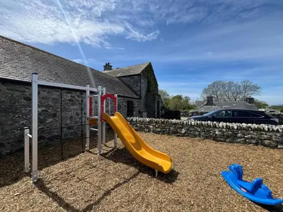 a playground with a slide in a yard at 2 Bed in Dyffryn Ardudwy oc-89438 in Dyffryn