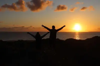 a couple of people standing on the beach with their arms out at Holiday Cottage in Snowdonia (Sleeps 10) in Harlech