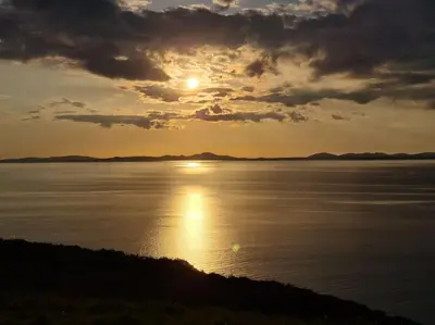 a sunset over a body of water with the sun setting at Holiday Cottage in Snowdonia (Sleeps 10) in Harlech