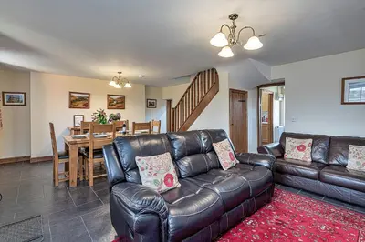 a living room with a leather couch and a dining room at Finest Retreats - Llechwedd Mawr in Talybont