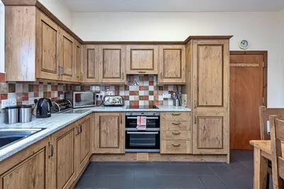 a kitchen with wooden cabinets and a stove top oven at Finest Retreats - Eithinog in Talybont