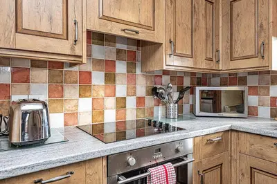 a kitchen with wooden cabinets and a stove top oven at Finest Retreats - Helygen in Talybont