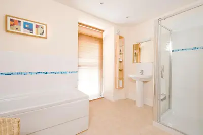 a bathroom with a shower and a tub and a sink at Fron Haul in Aberdyfi