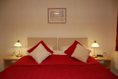 a bedroom with a red and white bed with two lamps at Fron Haul in Aberdyfi