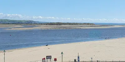 a beach with people on the sand and water at Fron Haul in Aberdyfi
