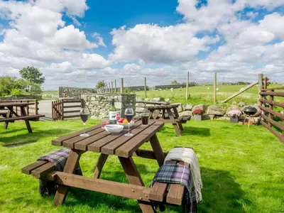 a picnic table with wine glasses on a field at 1 Bed in Dyffryn Ardudwy oc-89395 in Dyffryn