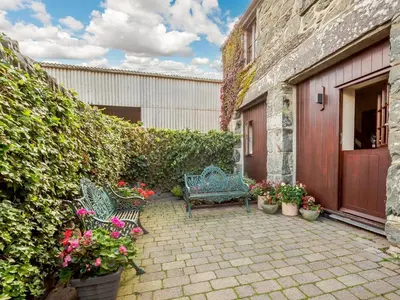 a patio with two benches and flowers in front of a building at 2 Bed in Dyffryn Ardudwy oc-89394 in Dyffryn