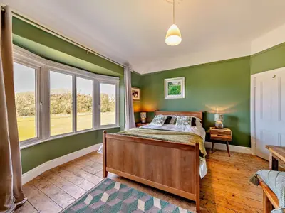 a bedroom with green walls and a bed and windows at 4 Bed in Friog 42772 in Fairbourne