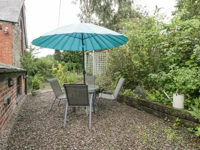 a table and chairs with an umbrella in a garden at The Old Bakehouse in Leominster