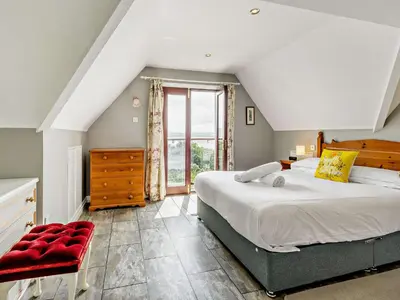a bedroom with a large bed and a red chair at 3 Bed in Aberdovey DY032 in Aberdyfi