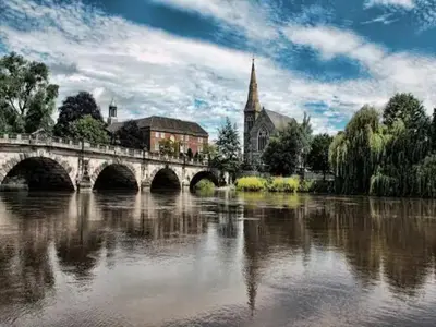 a bridge over a river in front of a church at Unique town centre apartment with vaulted ceiling - Pass the Keys in Shrewsbury