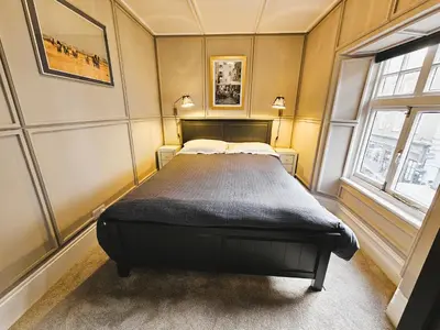 a bedroom with a bed in a room with two windows at Unique town centre apartment with vaulted ceiling - Pass the Keys in Shrewsbury