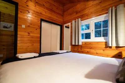 a bedroom with a large bed in a wooden room at Rural Log Cabin in Snowdonia near Coed y Brenin by Seren Short Stays in Ffestiniog