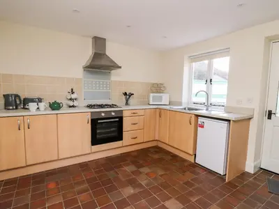 a kitchen with wooden cabinets and a stove top oven at Railway Station Cottage in Llandrindod Wells