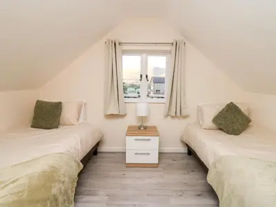 two twin beds in a room with a window at Railway Station Cottage in Llandrindod Wells
