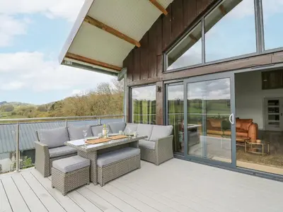 a patio with chairs and a table on a deck at Barcud Coch - Red Kite in Welshpool