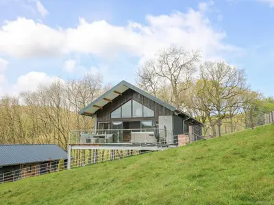 a house on top of a grassy hill at Barcud Coch - Red Kite in Welshpool