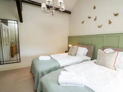 a bedroom with two beds and a mirror at Dant Y Llew in Bow Street