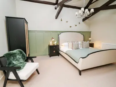 a bedroom with a large bed and a chair at Llygad Y Dydd in Bow Street