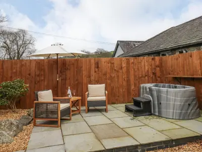 a patio with two chairs and a grill and an umbrella at Llygad Y Dydd in Bow Street