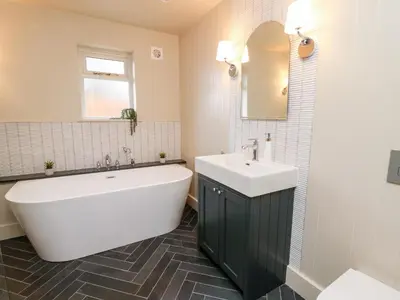 a bathroom with a white tub and a sink and a mirror at Llygad Y Dydd in Bow Street