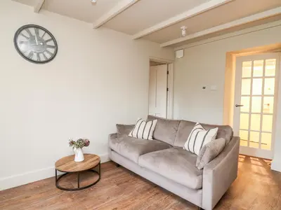 a living room with a couch and a clock on the wall at Llygad Y Dydd in Bow Street