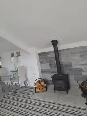 a living room with a wood stove and a table at The Old Fire Station in Tregaron