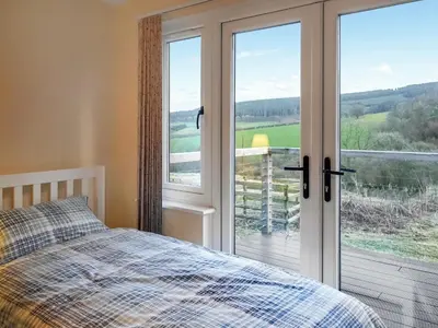 a bedroom with a bed and a sliding glass door at The Old Stables in Presteigne