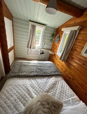 a bedroom with a bed in a room with wooden walls at Snug and cosy log cabin. in Trawsfynydd