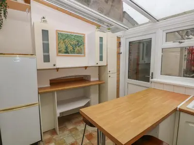 a kitchen with white cabinets and a wooden table at Rhif Deg in Brecon