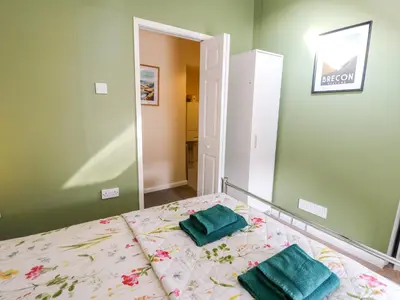 a bedroom with a bed with two green pillows on it at Rhif Deg in Brecon