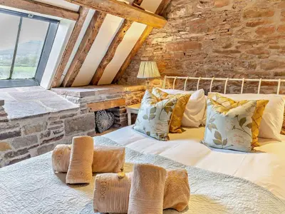 a large bed in a room with a stone wall at 3 Bed in Brecon oc-bn430 in Llangorse