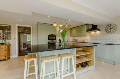 a kitchen with green cabinets and a counter with stools at 4 Bed in Oswestry oc-87477 in Llansilin