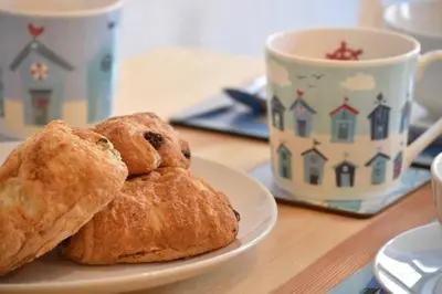 two pastries on a plate next to a cup of coffee at Isfryn, holiday home in Aberdyfi in Aberdyfi