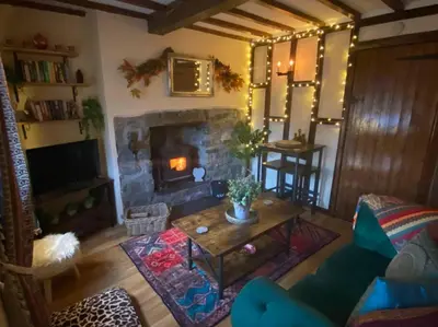 a living room with a fireplace and a table at Maytree Cottage. Compact home in Mid Wales. in Llanrhaeadr-ym-Mochnant