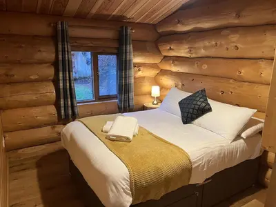 a bedroom with a bed in a log cabin at Mountain Edge Resort Lodge 1 with Hot Tub in Church Stretton