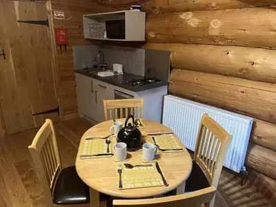a wooden table with chairs and a tea kettle on it at Mountain Edge Resort Lodge 2 with Hot Tub in Church Stretton